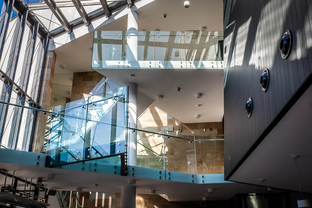 Zbliżenie na przeszklone poręcze na piętrach budynku / A close-up of the glass railings on the floors of the building
