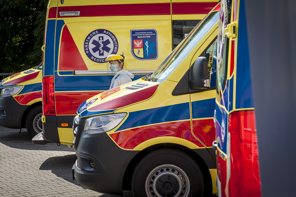 Ratowniczka medyczna idzie pomiędzy ambulansami