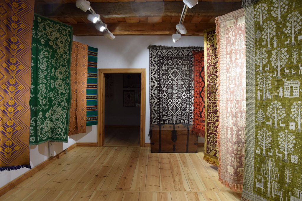 Wystawa sztuki ludowej wewnątrz dworu – dekoracyjne tkaniny 