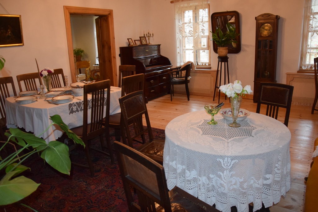 Wystawa dworskiego wnętrza – salon ze stołem jadalnym, meble, pianino