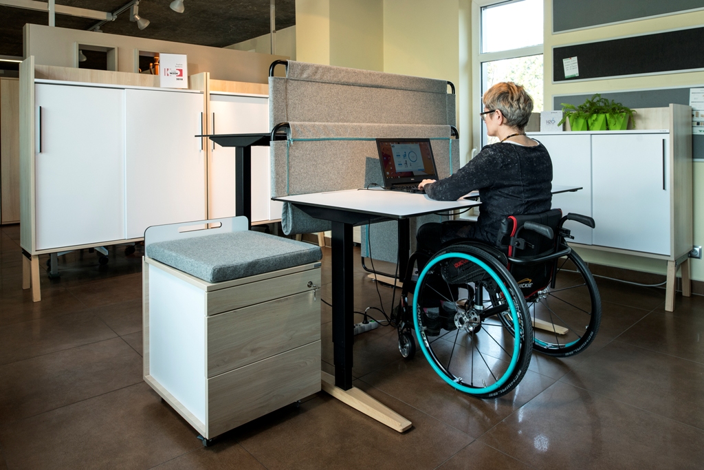 Kobieta na wózku pracuje przy biurku firmy TOBO / Woman on the wheelchair is working at the desk