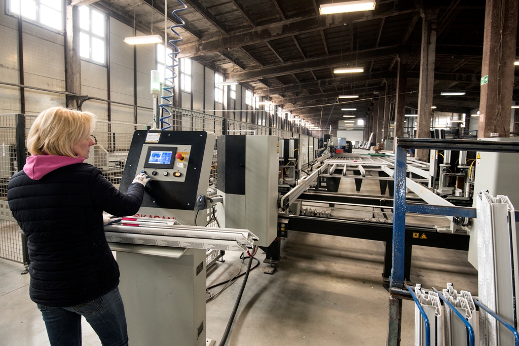 Pracownica firmy operuje maszyną w hali produkcyjnej