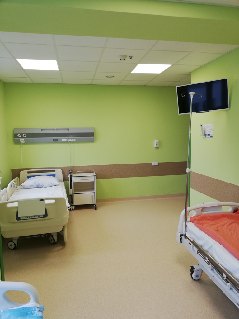 Sala szpitalna z dwoma łóżkami i panelem nad łóżkiem