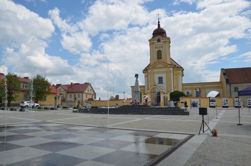 Rynek w Choroszczy, na pierwszym planie fornatnny, w tle kościół. 