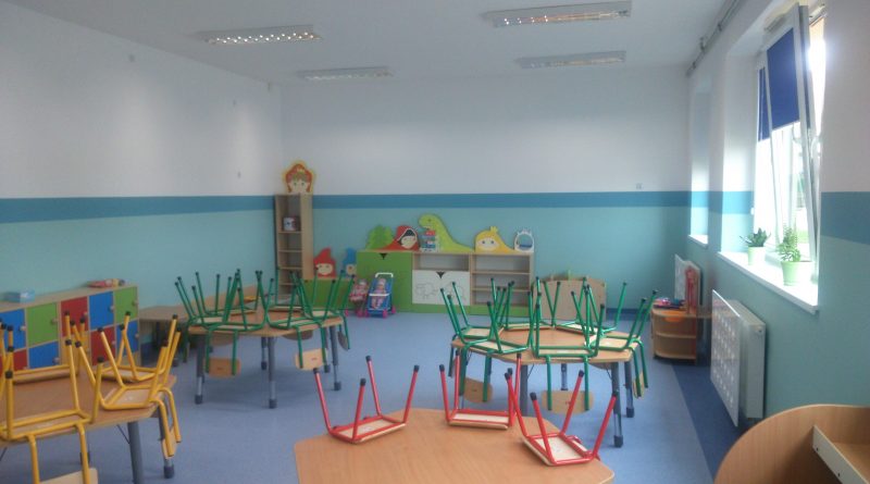 Pomieszczenie przedszkolne, okrągłe stoły z krzesełkami, regały z zabawkami