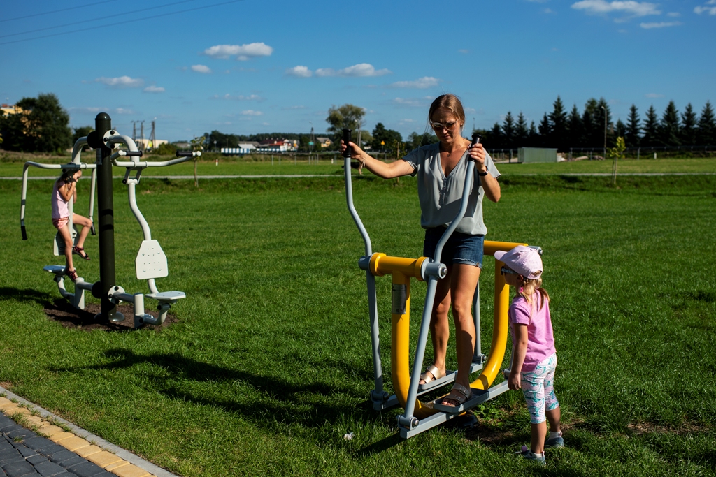 Kobieta z dziećmi używa sprzętów na siłowni pod chmurką